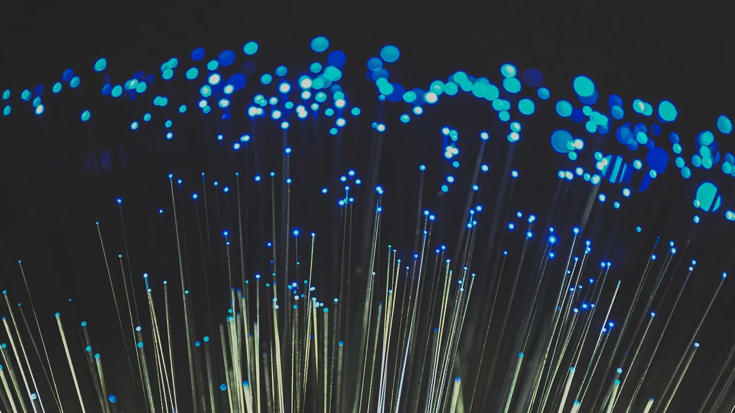 ChatGPT ha detto: Un'immagine che mostra un primo piano di cavi in fibra ottica con luci blu brillanti che emergono da essi, simboleggiando la connessione rapida e il flusso di dati nell'era digitale, un concetto fondamentale nell'Internet of Things (IoT) e nelle reti avanzate di comunicazione.