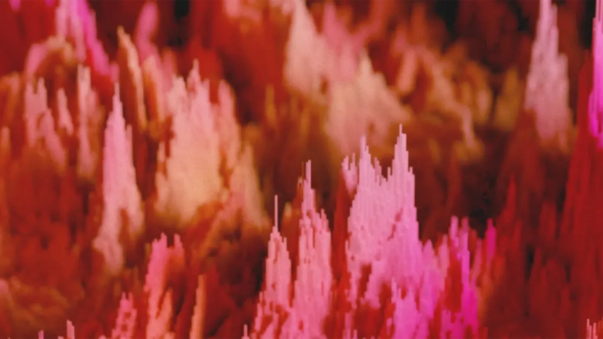Un'immagine astratta che rappresenta un insieme di piccole strutture verticali colorate in sfumature di rosa e rosso. Queste strutture hanno l'aspetto di piccole colonne o picchi, creando un effetto di profondità e movimento, simile a un paesaggio digitale o a una visualizzazione dati.